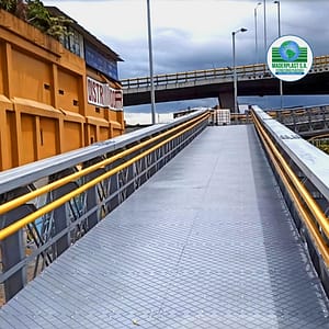 Vista frontal de puente peatonal con piso en polipropileno Maderplast y barandas amarillas, diseñado para acceso urbano seguro y resistente.